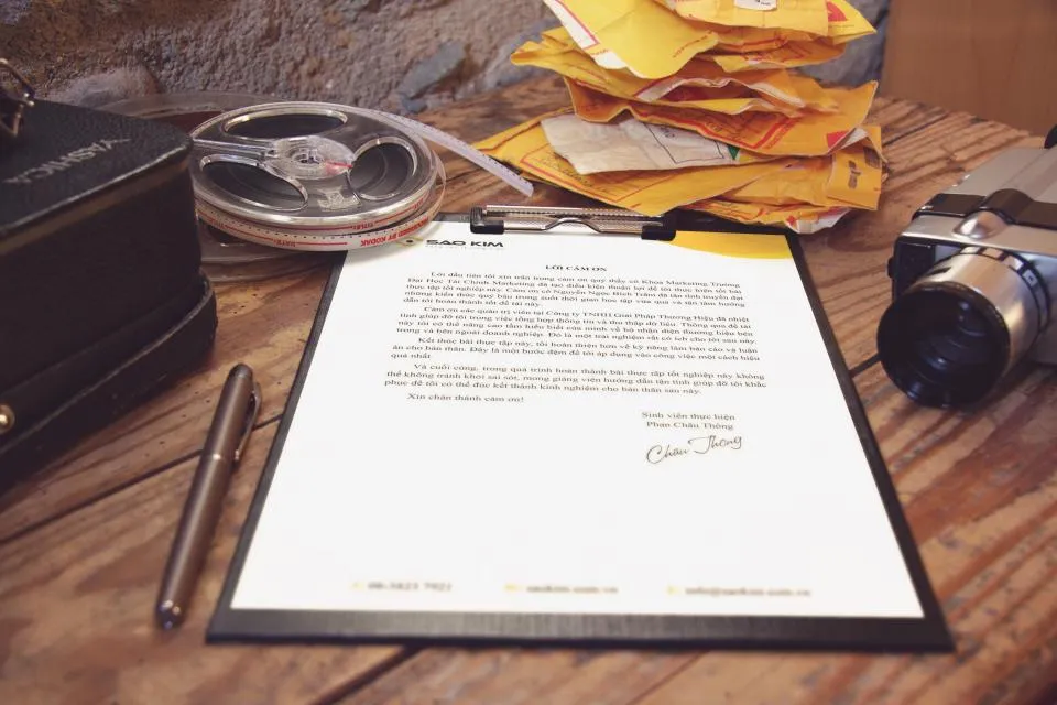 Signed letter on a clipboard beside a pen on a wooden desk